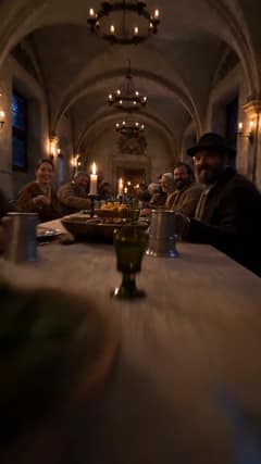 Hostina pri dlhom stole v klenutej sieni osvetlenej sviečkami